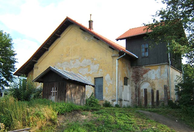 Zadní trakt výtopny s věží vodárny a dřevěnou budkou vodárenské studny v popředí.