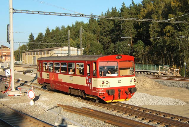 Středem rozestavěné stanice Pňovany projíždí motorový vůz 810.306.